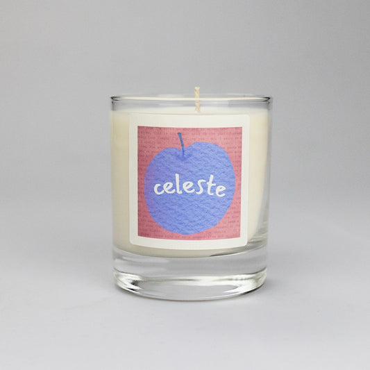 Product photo of scented soy candle Celeste, made by BONKI. Candle in glass jar. Pink label with purple peach and writing "Celeste".